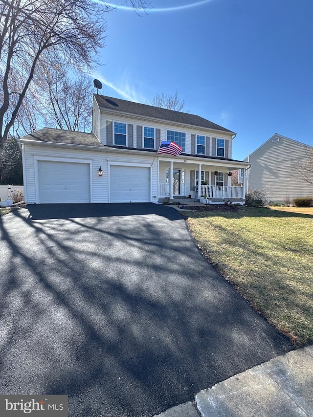 view of front facade featuring a front yard, a garage, covered porch, and driveway