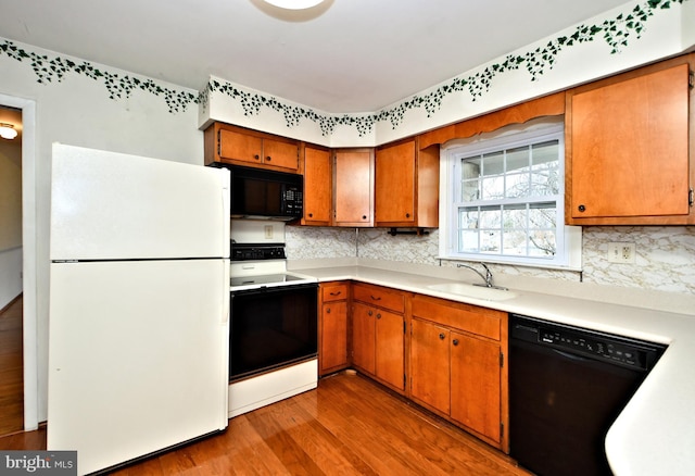 kitchen with sink, backsplash, light hardwood / wood-style floors, and black appliances