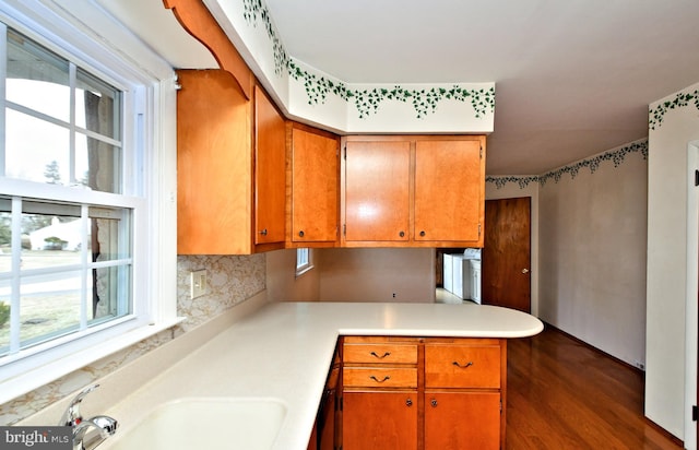 kitchen with sink, tasteful backsplash, dark hardwood / wood-style flooring, washer / dryer, and kitchen peninsula