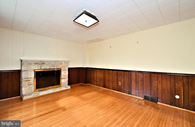 unfurnished living room with hardwood / wood-style flooring, wooden walls, and a fireplace