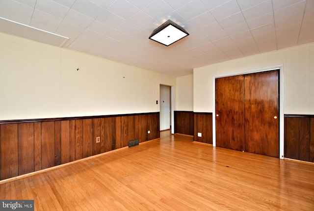 spare room featuring wood walls and light hardwood / wood-style flooring