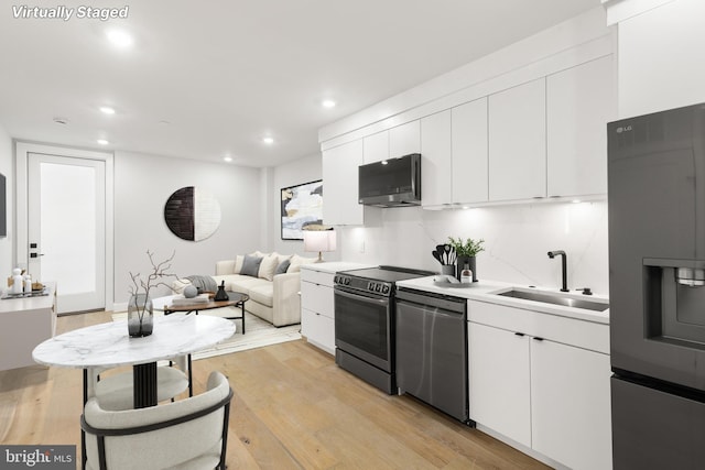 kitchen featuring stainless steel appliances, light hardwood / wood-style floors, sink, and white cabinets