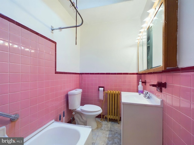 bathroom with tile walls, radiator heating unit, vanity, tile patterned floors, and a bathing tub