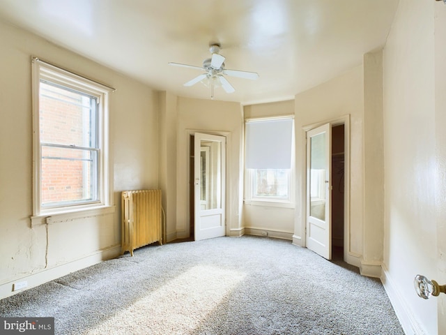 unfurnished bedroom with ceiling fan, radiator heating unit, and light carpet