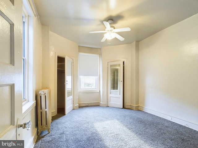 unfurnished bedroom with ceiling fan, carpet flooring, and radiator