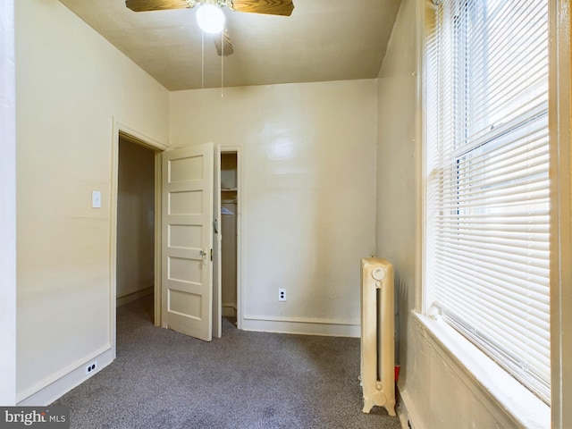 carpeted empty room featuring radiator heating unit and ceiling fan