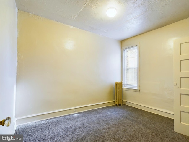 unfurnished room with dark colored carpet and a textured ceiling