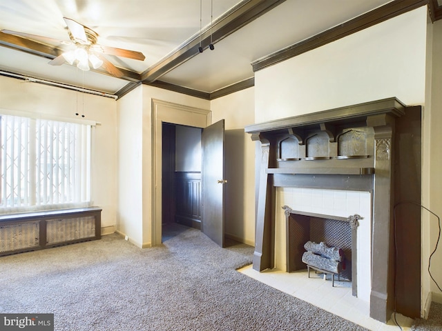 unfurnished living room featuring crown molding, radiator heating unit, carpet flooring, ceiling fan, and a fireplace