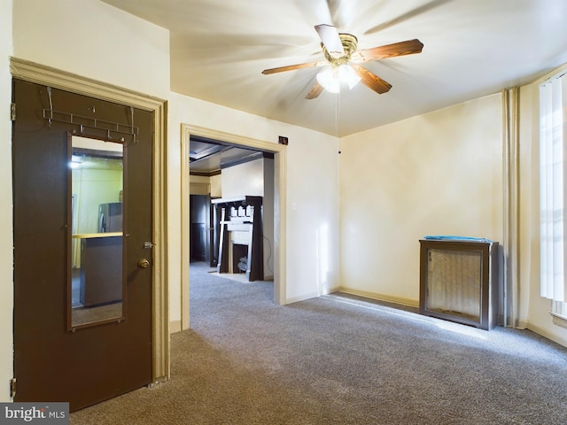 empty room with a fireplace, ceiling fan, and carpet