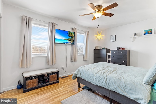 bedroom with multiple windows, visible vents, baseboards, and wood finished floors