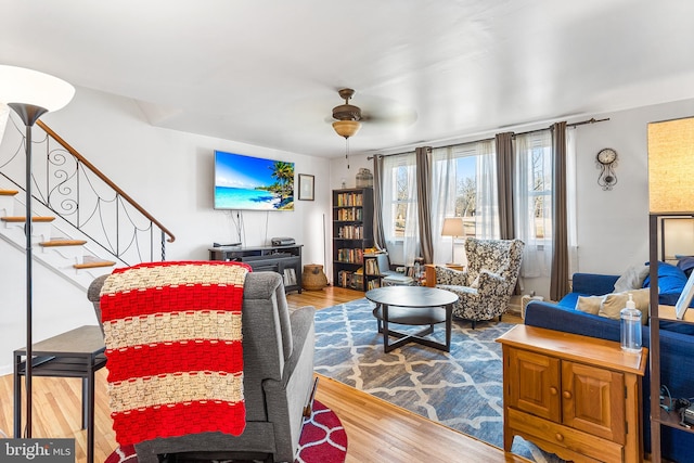 living area featuring stairway, wood finished floors, and a ceiling fan