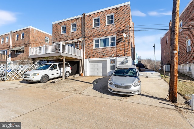 rear view of property featuring a garage, driveway, and brick siding