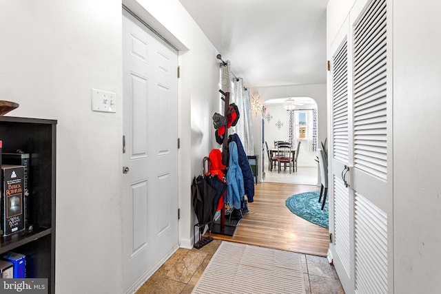 corridor featuring light wood-type flooring and arched walkways