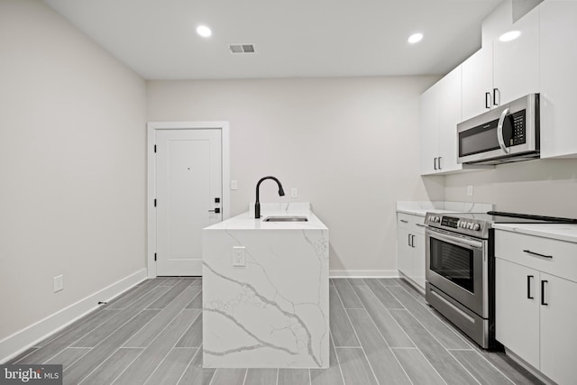 kitchen with white cabinetry, appliances with stainless steel finishes, sink, and light stone counters