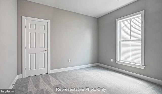 carpeted spare room featuring baseboards