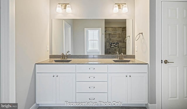 full bathroom featuring double vanity, a tile shower, and a sink