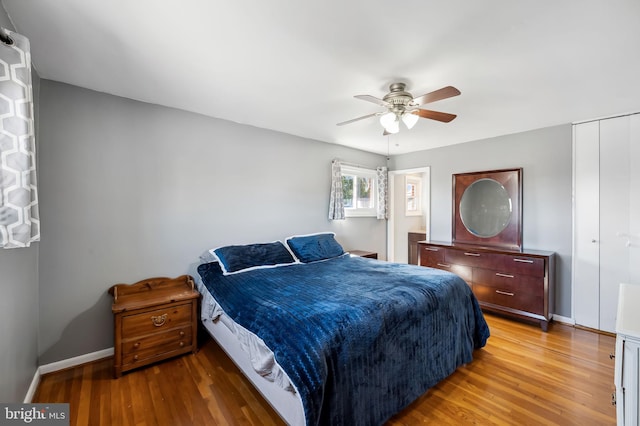 bedroom featuring a closet, baseboards, light wood-style floors, and ceiling fan