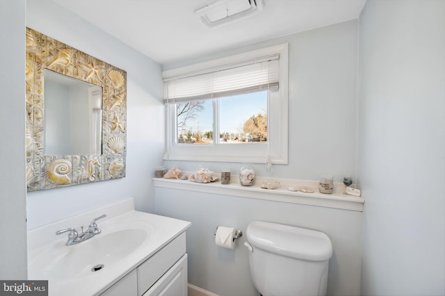 half bath with vanity, toilet, and visible vents