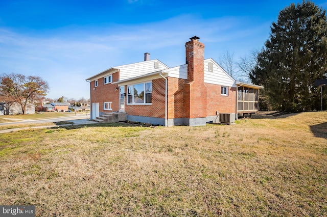 view of side of property featuring cooling unit, brick siding, a chimney, and a lawn