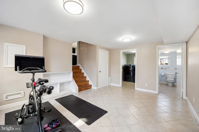 exercise room featuring baseboards, independent washer and dryer, and light tile patterned flooring