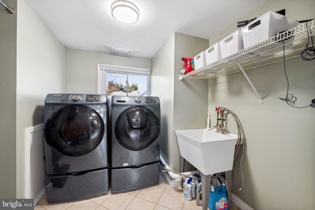 washroom with tile patterned flooring, laundry area, washing machine and dryer, and baseboards