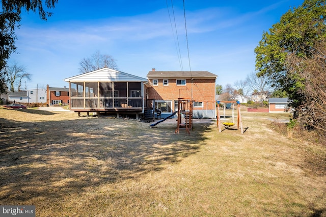 back of house with a yard, a sunroom, a chimney, a playground, and brick siding