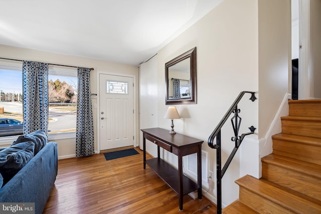 entrance foyer with stairs, baseboards, visible vents, and wood-type flooring