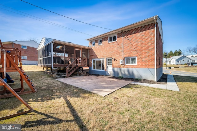 rear view of property featuring brick siding, a playground, a yard, a sunroom, and a patio area