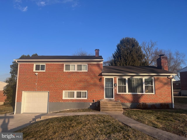 tri-level home with a garage, brick siding, concrete driveway, and a chimney