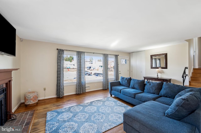 living area with stairs, baseboards, wood finished floors, and a tiled fireplace