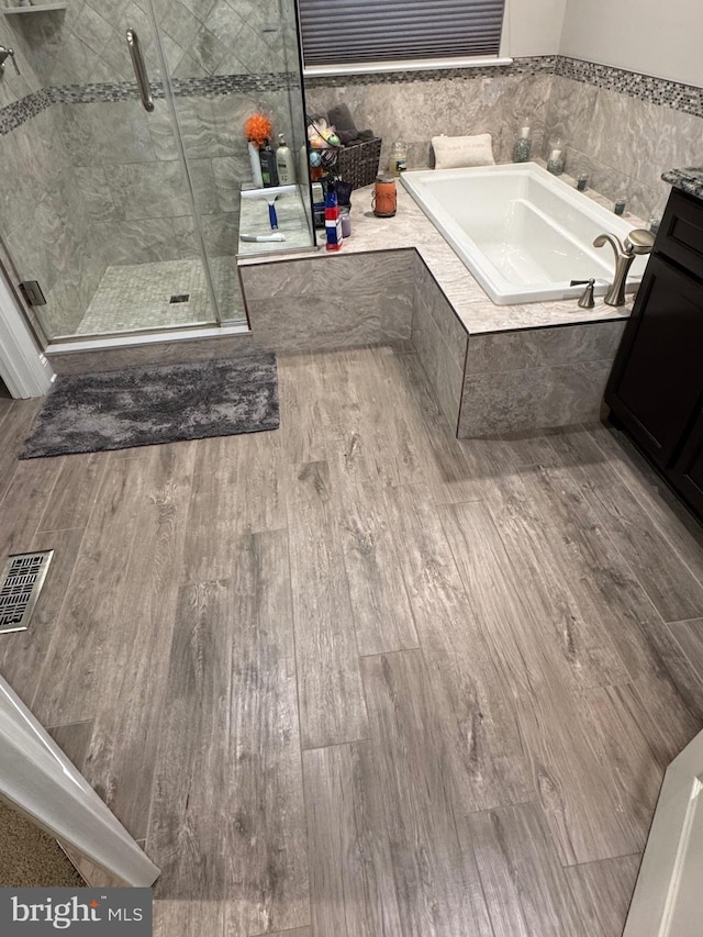 bathroom featuring hardwood / wood-style flooring, vanity, and separate shower and tub