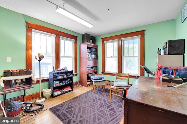 office featuring a baseboard heating unit, baseboards, and wood finished floors