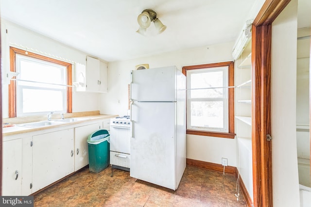 kitchen with white cabinets, light countertops, white appliances, and a sink