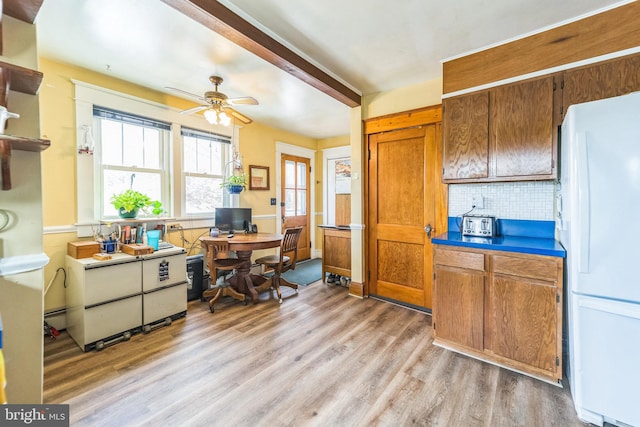 kitchen featuring light wood-style flooring, freestanding refrigerator, decorative backsplash, brown cabinets, and ceiling fan