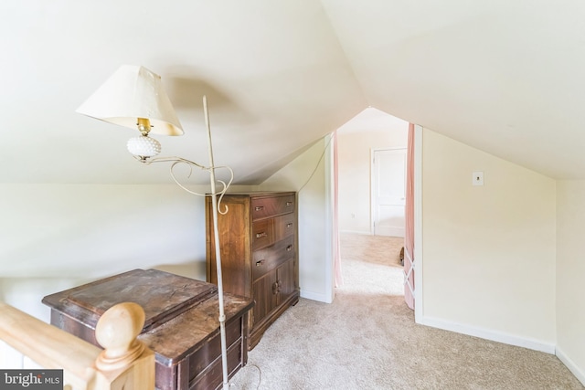 additional living space with vaulted ceiling, baseboards, and light carpet