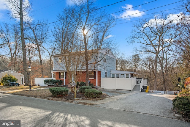 view of front facade with brick siding, fence, and driveway