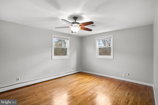 spare room with a baseboard radiator, visible vents, a wealth of natural light, and wood finished floors