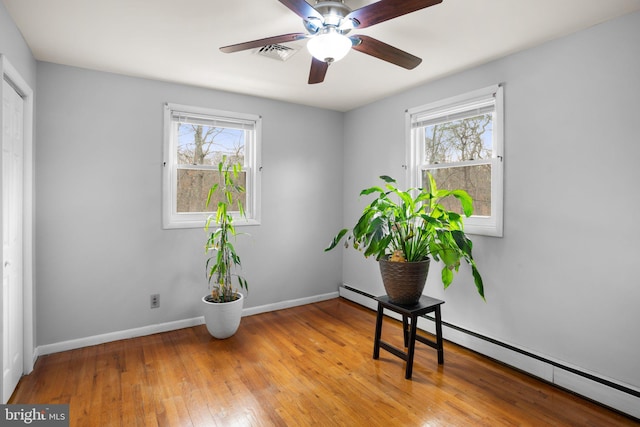 interior space featuring a healthy amount of sunlight, light wood finished floors, visible vents, and baseboard heating