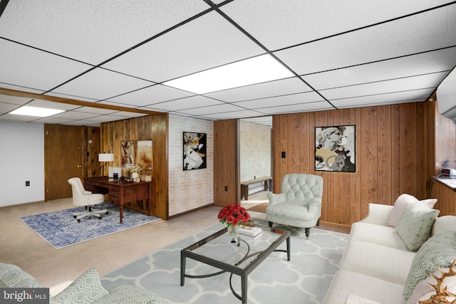 living room with wooden walls, a drop ceiling, and light colored carpet