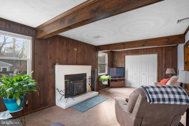 living area featuring wooden walls, visible vents, beam ceiling, and light colored carpet