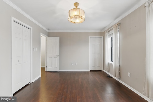 unfurnished bedroom with crown molding, dark wood-style floors, baseboards, and visible vents