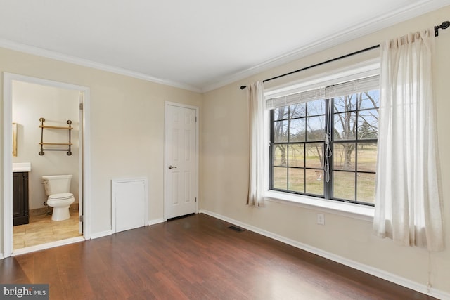 unfurnished bedroom with visible vents, baseboards, dark wood-type flooring, and ornamental molding