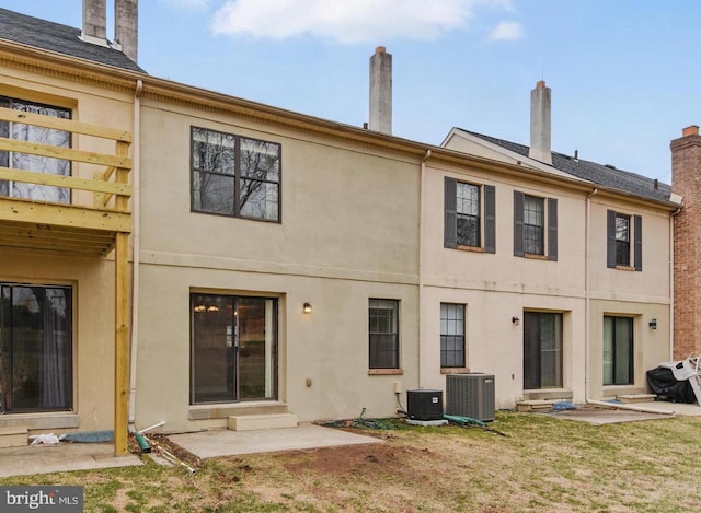 rear view of property featuring entry steps, central AC, and stucco siding