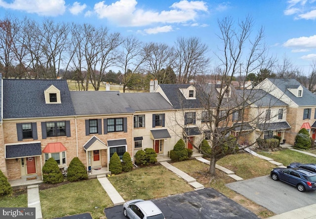 multi unit property with a front lawn, a residential view, and roof with shingles