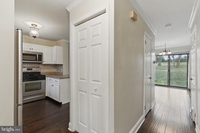 hallway featuring dark wood finished floors, crown molding, baseboards, and a chandelier