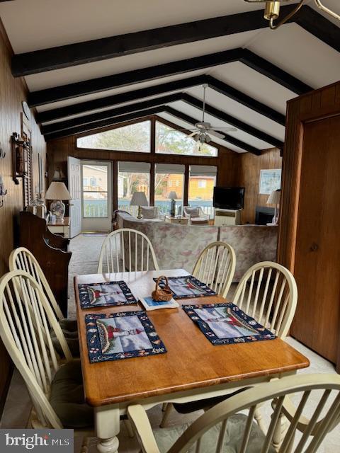 dining room featuring ceiling fan, lofted ceiling with beams, and wood walls