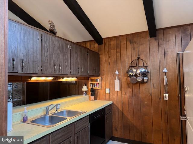 kitchen with sink, beam ceiling, wooden walls, and black dishwasher