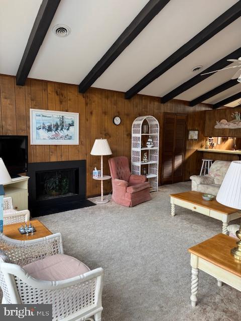 living room with carpet floors, wooden walls, and beam ceiling