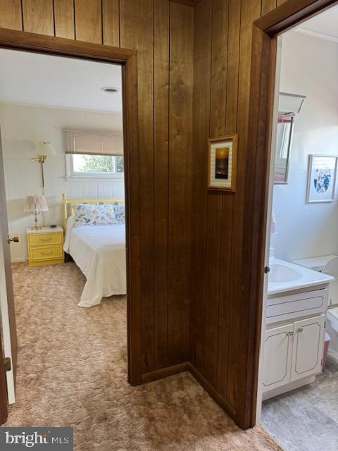 bedroom with light carpet and wood walls