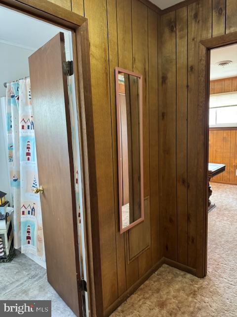 hallway featuring light carpet and wood walls